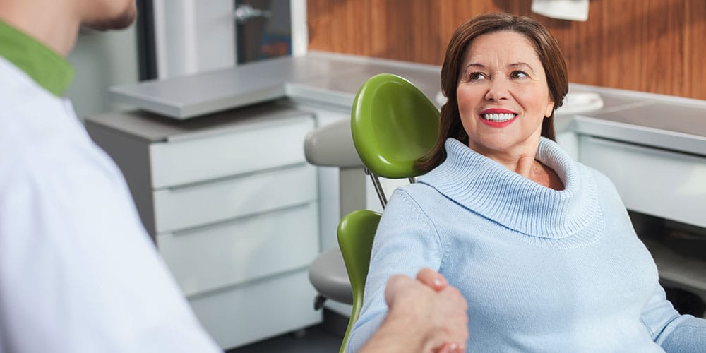 middle aged woman shaking dentist's hand