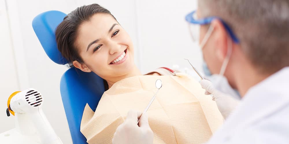 young woman in dentist chair smiling at the dentist